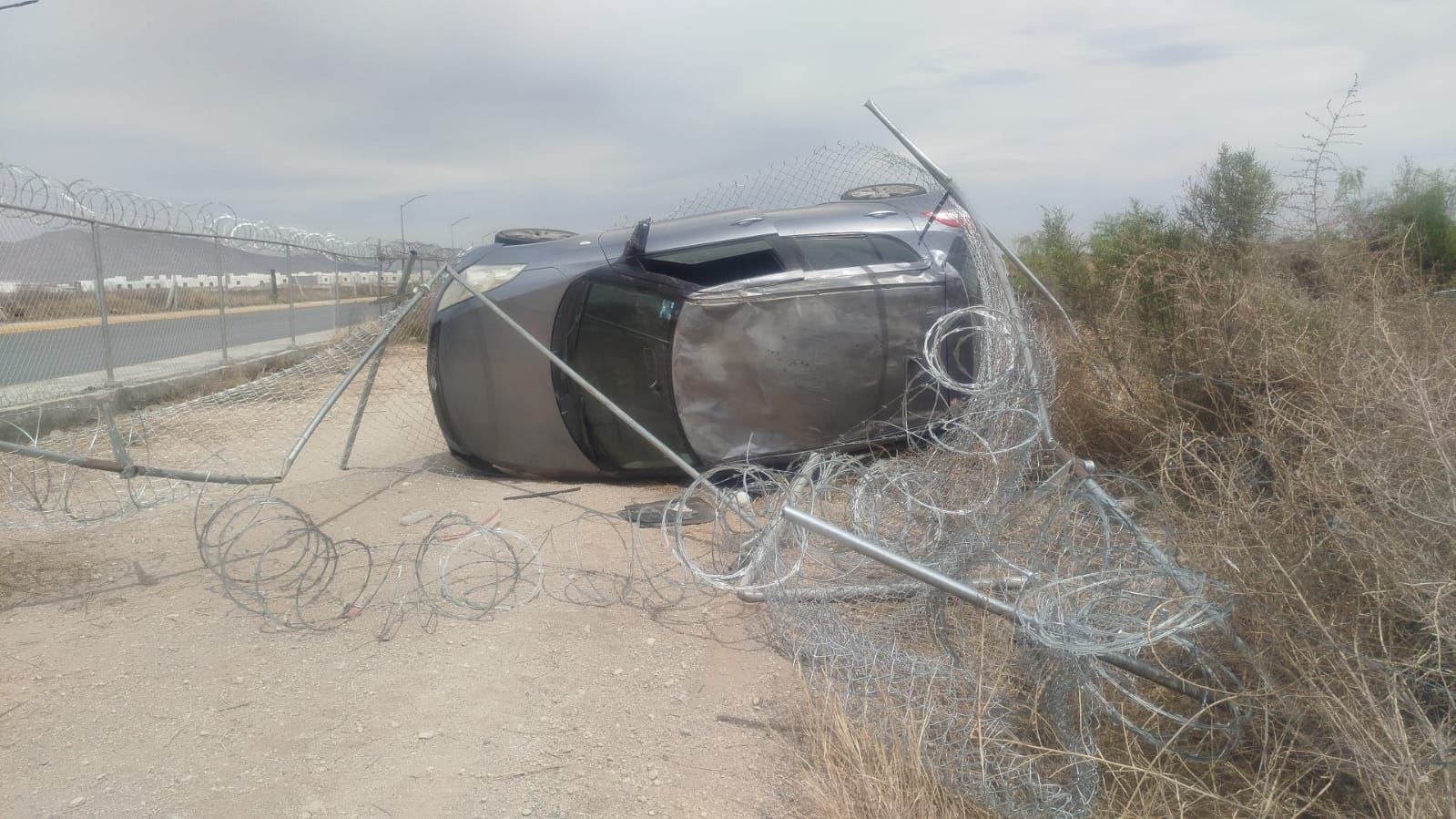 Otro auto se vuelca y daña la malla del aeropuerto de RA